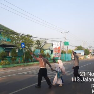 Satlantas Polres Bima Kota Bantu Anak Sekolah Menyeberang Jalan dalam Gatur Pagi