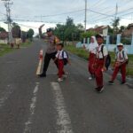 Bhabinkamtibmas Polsek Utan Berikan Pelayanan Prima dengan Membantu Anak-Anak Sekolah Menyeberang Jalan