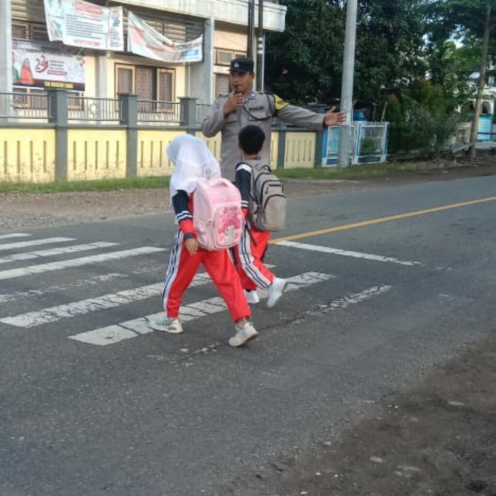 Wujud Polisi Humanis, Brigadir Wawan Satria Atur Lalu Lintas Saat Anak Sekolah di Desa Goa